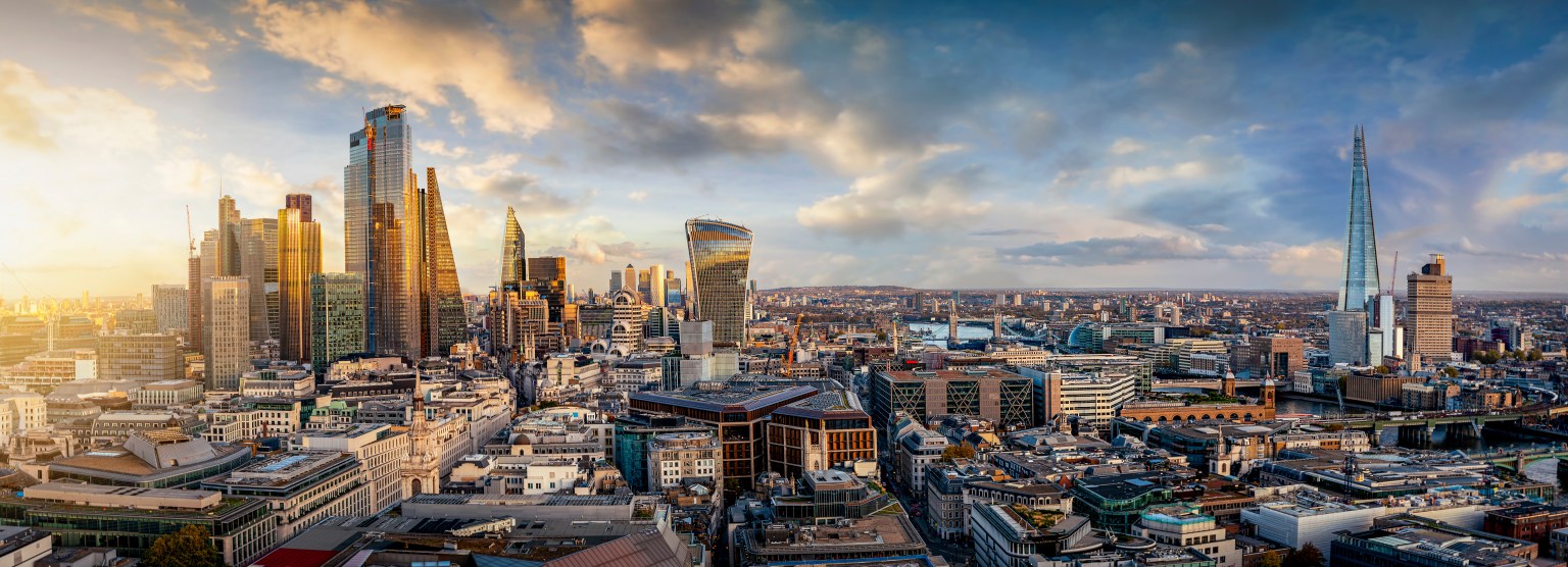 Panoramic view of London skyline at sunset featuring The Shard and modern skyscrapers in the financial district