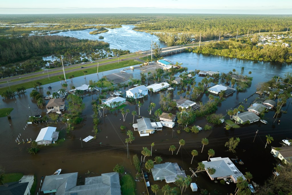 Aerial view of flooded neighborhood and submerged homes after hurricane with nearby river overflow